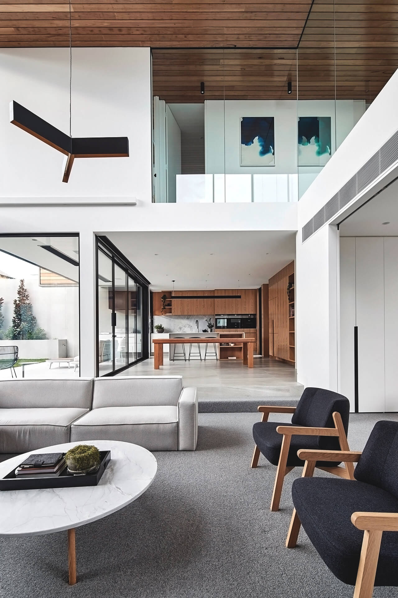 Interior of modern home showing downstairs, upstairs, and outside areas with modern furniture in the foreground and a modern kitchen in the background.