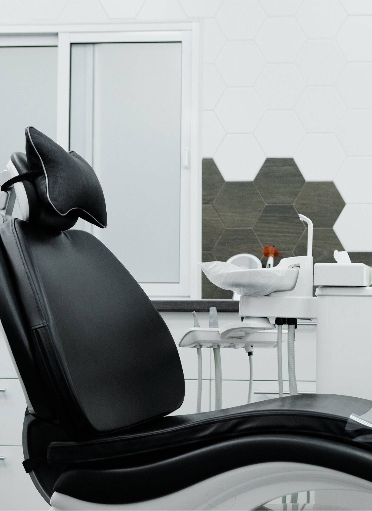 Black leather dental chair in sleek, modern dentist's office.