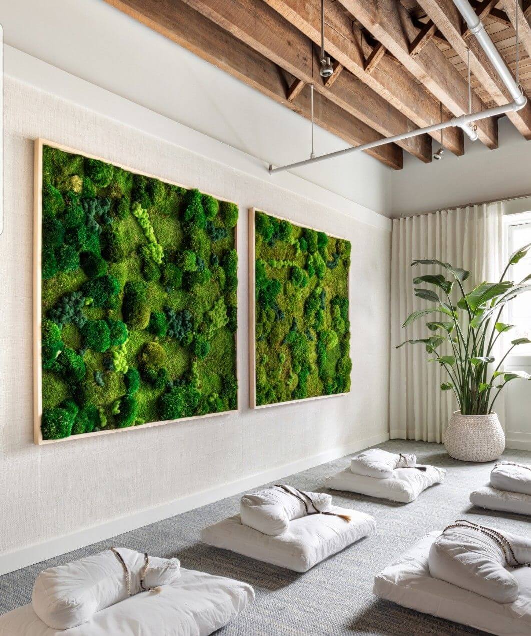 Conceptual modern interior with white cushions on the ground and moss on the walls.