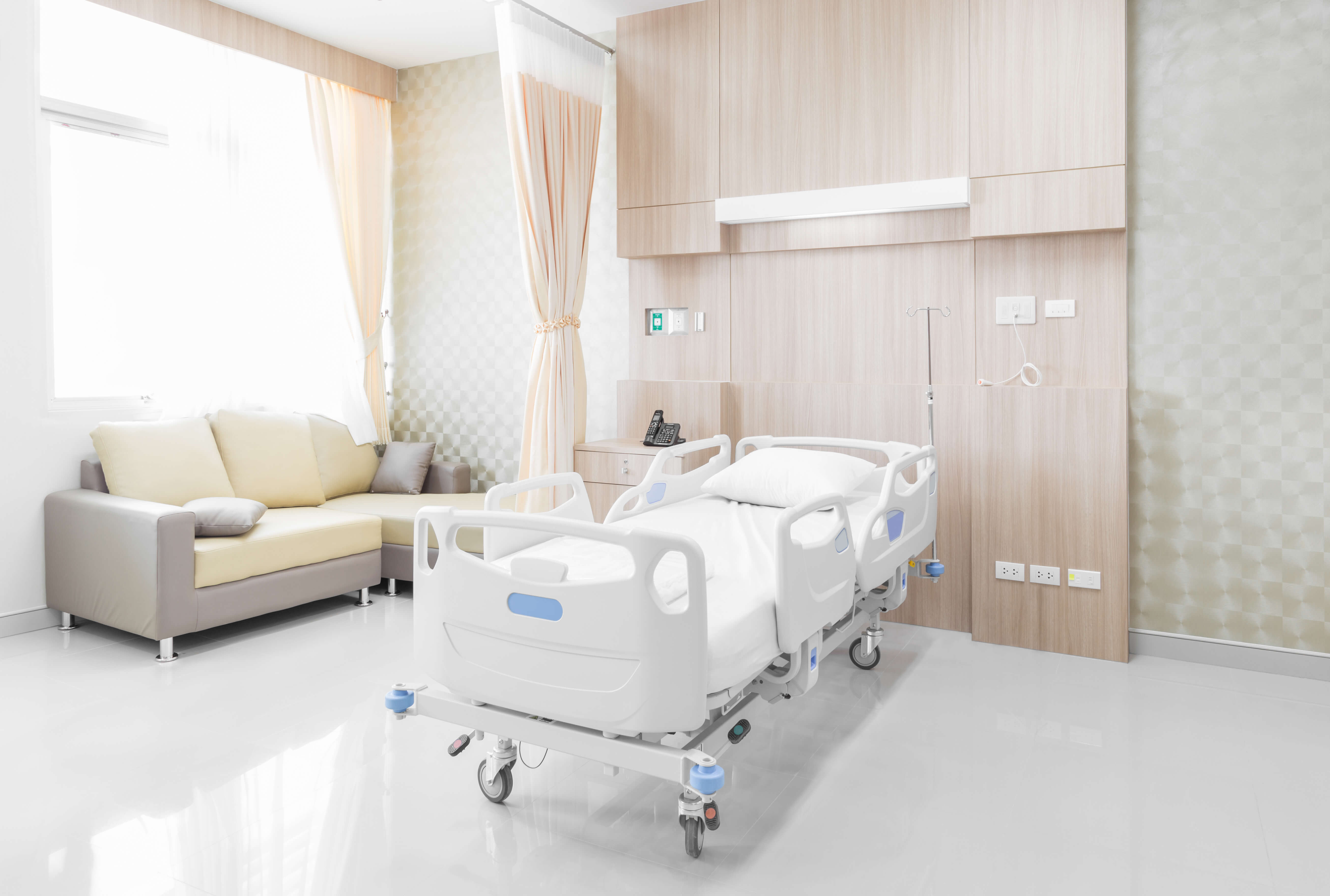 Hospital bed and couch in modern hospital room.