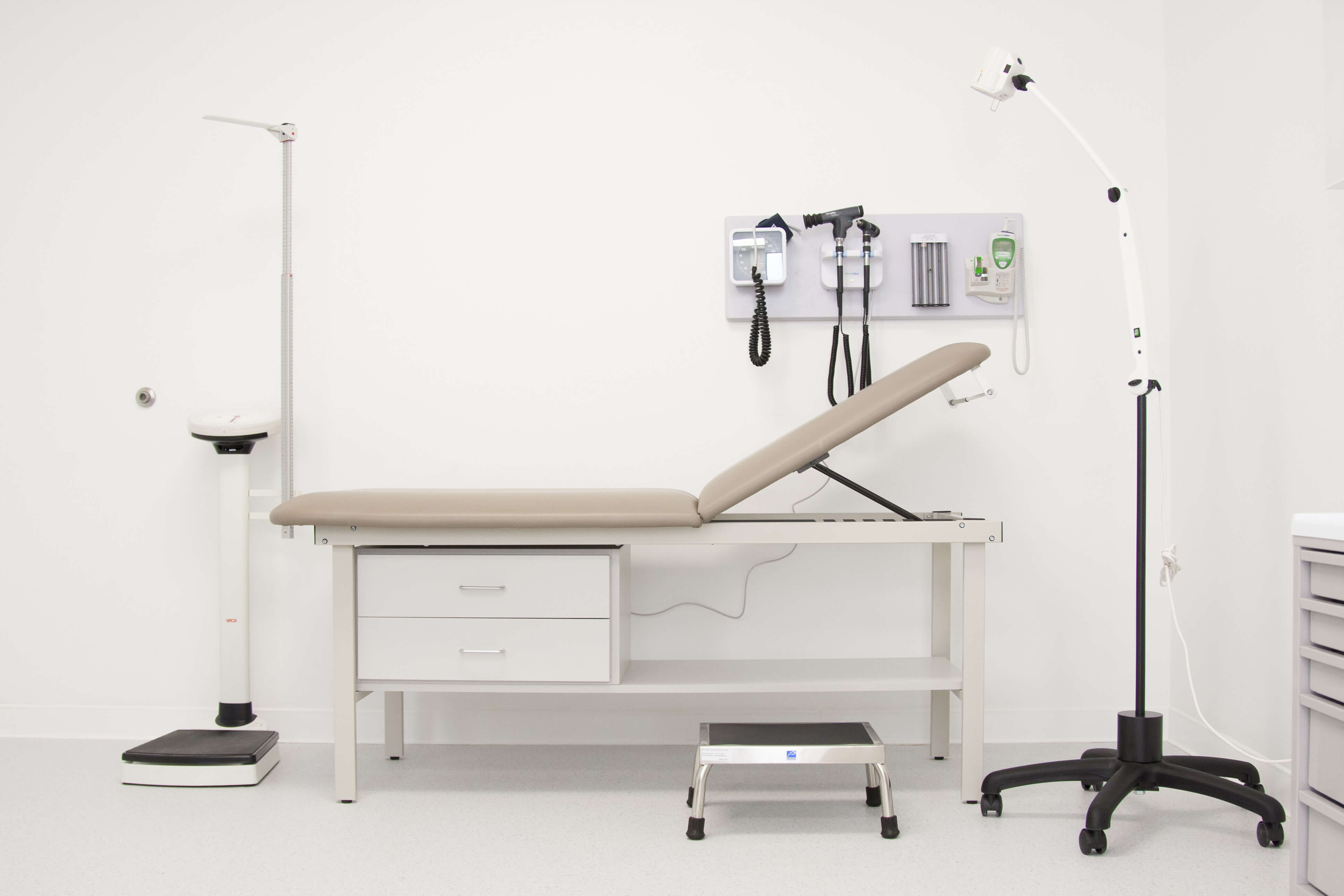 Doctor's office examination room with examination table and basic medical equipment.